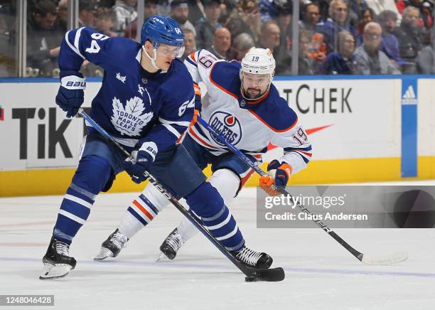 Devin Shore of the Edmonton Oilers skates to check David Kampf of the Toronto Maple Leafs during an NHL game at Scotiabank Arena on March 11, 2023 in...