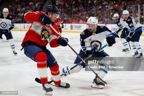 Eetu Luostarinen of the Florida Panthers crosses sticks with Dylan DeMelo of the Winnipeg Jets at the FLA Live Arena on March 11, 2023 in Sunrise,...