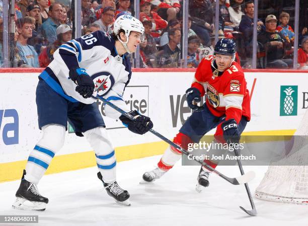 Sam Reinhart of the Florida Panthers defends against Morgan Barron of the Winnipeg Jets as he passes the puck from behind the net during second...
