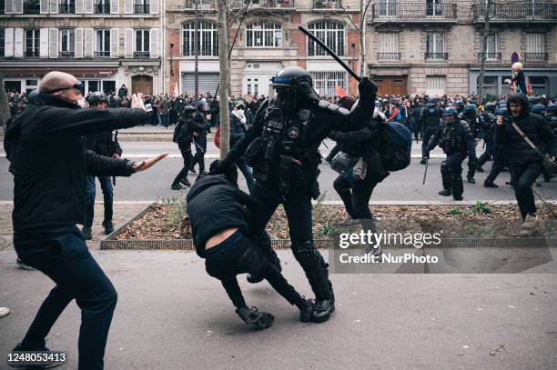 Riot police officer bludgeons a demonstrator dressed all in black during clashes between CRS and Black bloc during a new demonstration in Paris as...