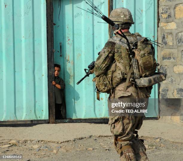 An Afghan boy watches US soldiers from Viper Company , 1-26 Infantry during a foot patrol in Sabari district in Khost province in the east of...