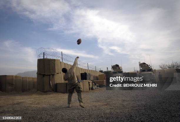 Soldiers from 1-320 Field Artillery Regiment, 2nd Brigade Combat, 101st Airborne Division play US football at Strong Point camp near the Khosrow Olia...