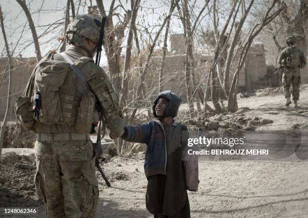 Lieutenant Nicholas Dieter from 1-320 Field Artillery Regiment, 2nd Brigade Combat, 101st Airborne Division shakes hands with an Afghan boy during a...