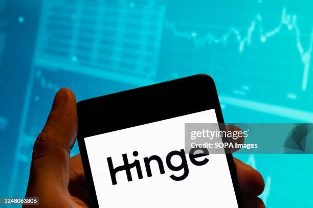 In this photo illustration, the online dating app Hinge logo is seen displayed on a smartphone with an economic stock exchange index graph in the...