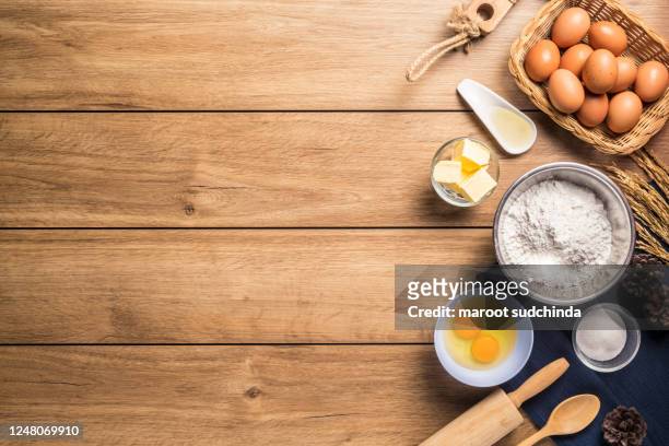 pictures of ingredients for making cakes bakery around, such as eggs, flour, sugar, butter, powder and equipment for making on a wooden floor, top view, with copy space. - butter making fotografías e imágenes de stock