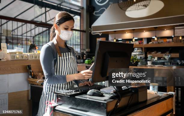 レストランで働くウェイトレスは、フェイスマスクを着用し、コンピュータに注文を置きます - reopening ストックフォトと画像