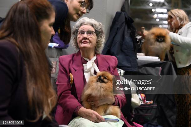 Woman sits with a Pomeranian dog as they watch the judging on the final day of the Crufts dog show at the National Exhibition Centre in Birmingham,...