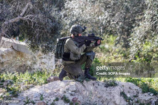 An Israeli soldier takes aim while guarding near the area where three Palestinians were shot in the village of Surra, west of Nablus, in the occupied...