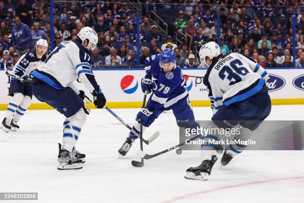 Ross Colton of the Tampa Bay Lightning shoots against Adam Lowry and Morgan Barron the Winnipeg Jets during the first period at Amalie Arena on March...