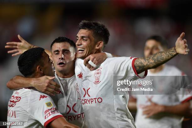 Juan Garro of Huracan celebrates with teammates Fernando Torrent and Lucas Carrizo after scoring the team's first goal during a match between...