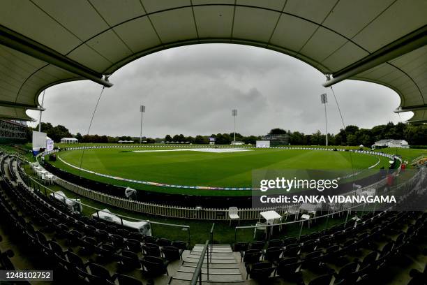 This photo shows a general view of the deserted stands and the partially covered pitch as rain delays play of the fifth day of the first Test match...