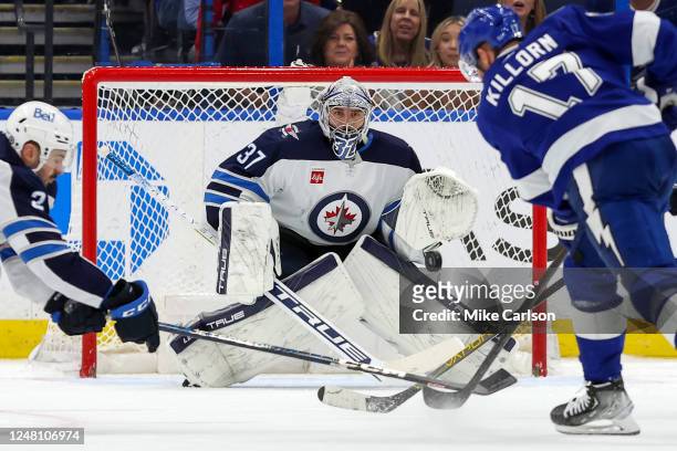 Connor Hellebuyck of the Winnipeg Jets makes a save against Alex Killorn of the Tampa Bay Lightning during the third period of a hockey game at the...