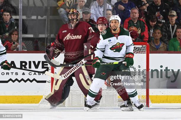 Karel Vejmelka of the Arizona Coyotes gets ready to make a save as teammate Victor Soderstrom battles for position with Ryan Reaves of the Minnesota...