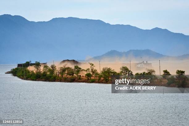 This picture taken on February 11, 2023 shows dust whipped up by workers using heavy equipment to remove soil containing nickel ore in Pomalaa in...