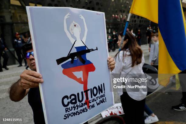 Members of the Ukrainian community in Mexico City hold banners and signs as they demonstrate outside the Pepsi Center where a Russian ballet...