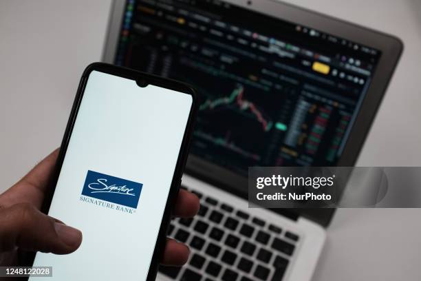 Signature Bank logo seen displayed on a smartphone screen with Exchange graph in the background in Chania, Greece on March 13, 2023. Signature Bank...