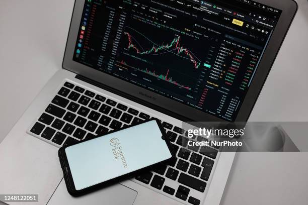 Signature Bank logo seen displayed on a smartphone screen with Exchange graph in the background in Chania, Greece on March 13, 2023. Signature Bank...