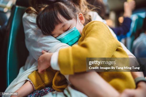 little girl with medical face mask sleeping soundly in mother’s arms while they are riding on bus - health epidemic stock pictures, royalty-free photos & images