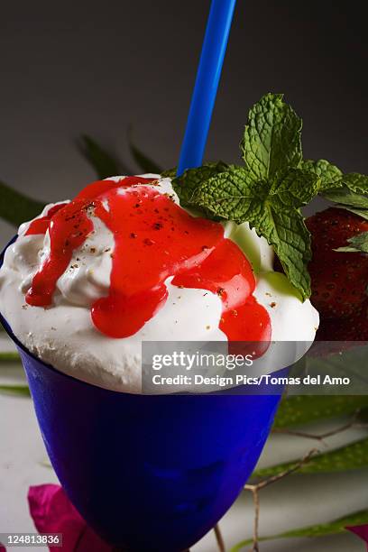 close-up of a blue cocktail glass filled with a creamy tropical drink dripping with strawberry syrup. - strawberry syrup stock pictures, royalty-free photos & images