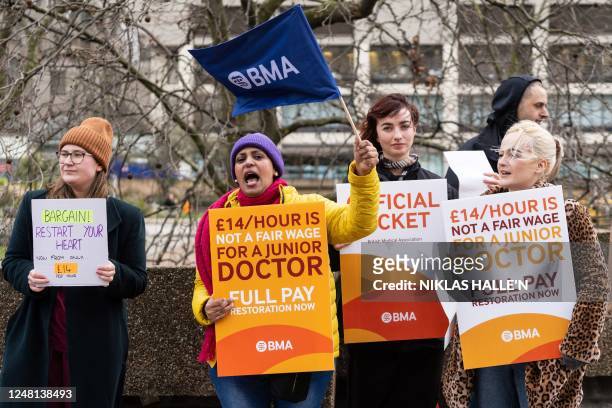 Demonstrators hold placards as they take part in a protest by junior doctors, amid a dispute with the government over pay, outside of Saint Thomas...