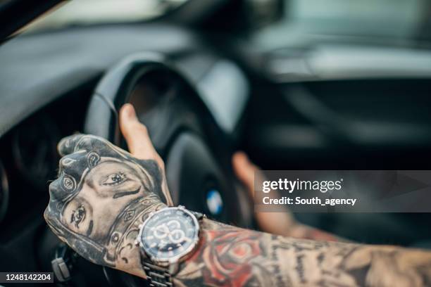 un jeune homme avec le corps entier couvert des tatouages conduisant une voiture - covered car photos et images de collection