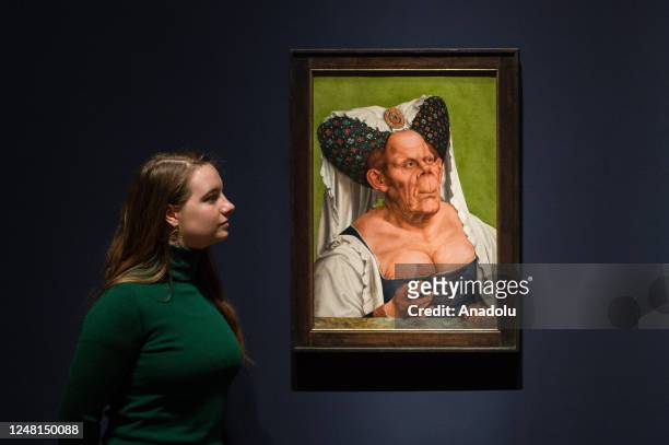 Gallery staff member poses with a painting titled 'An Old Woman ' by Quinten Massys during a photocall for The Ugly Duchess: Beauty and Satire in the...