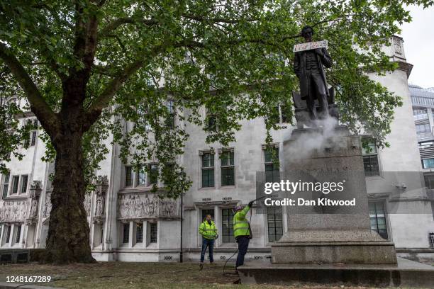 Worker cleans a statue of Abraham Lincoln in Parliament Square that had been spray painted with the words 'we will succeed' on June 08, 2020 in...