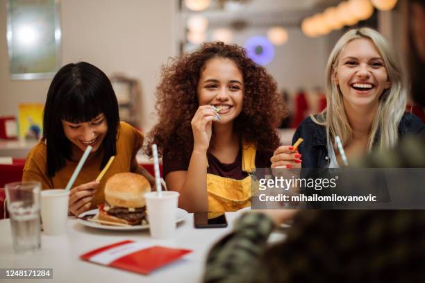 tucking in un ottimo cibo - adults eating hamburgers foto e immagini stock
