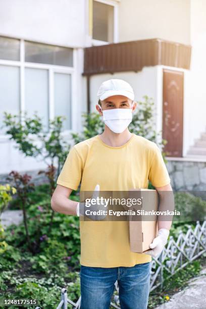 man from delivery service in protective gloves holding box. - entrega sin contacto fotografías e imágenes de stock