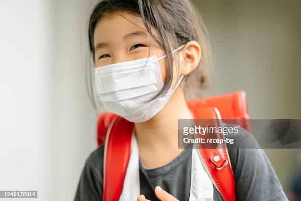 verticale de la fille heureuse d’école primaire d’âge - face mask coronavirus photos et images de collection