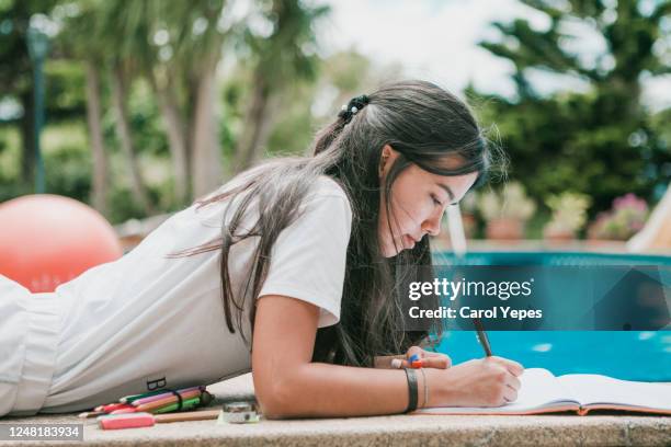 female teenager doing homeworks in back yard in a sunny day - summer school stock pictures, royalty-free photos & images