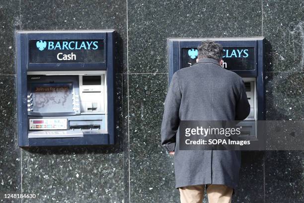 Man uses a cash point machine outside a branch of Barclays Bank in central London.
