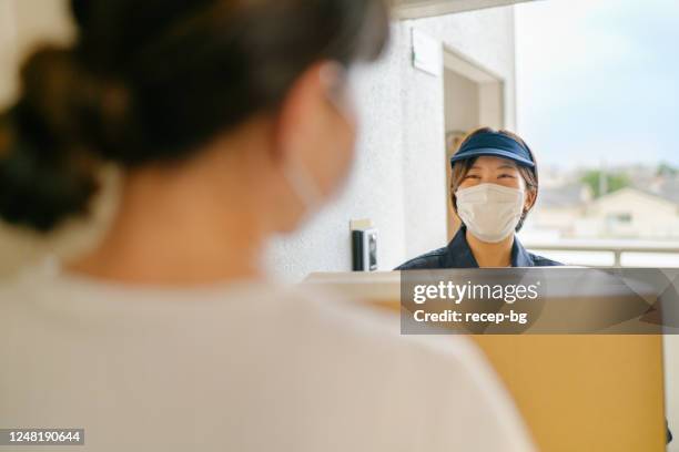 delivery person wearing protective face mask and delivering package to costumer - supermarket delivery stock pictures, royalty-free photos & images