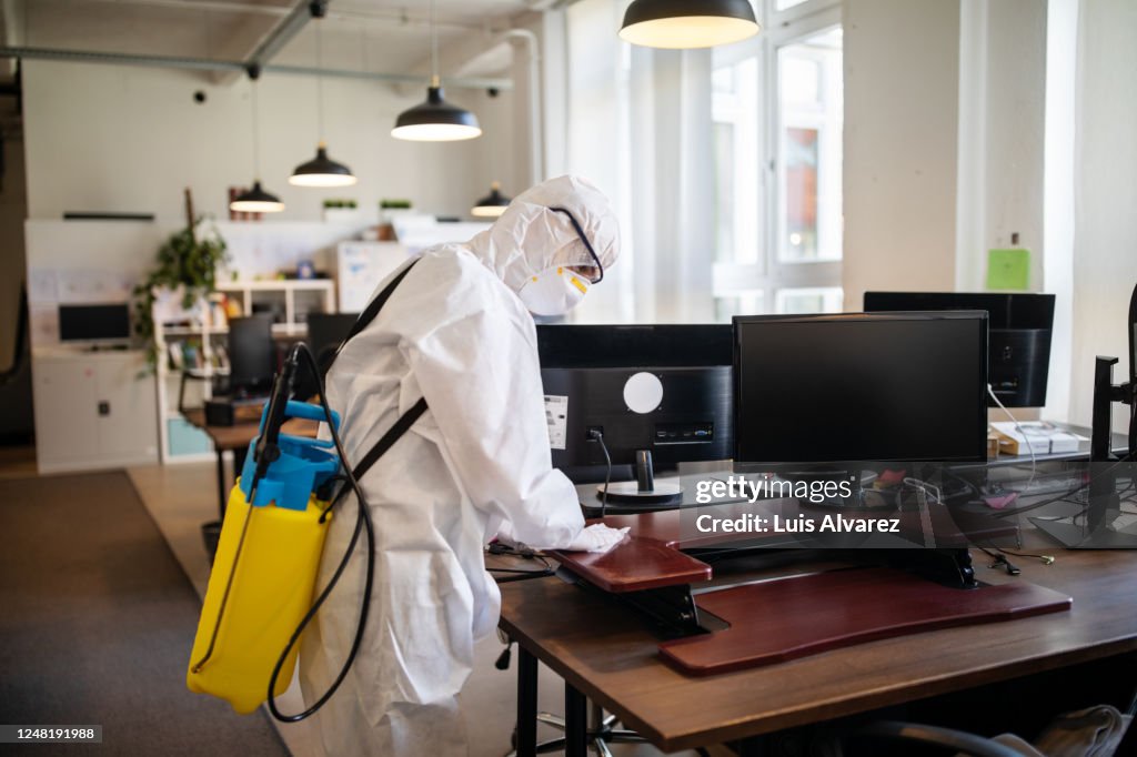 Worker cleaning and disinfecting the office desks