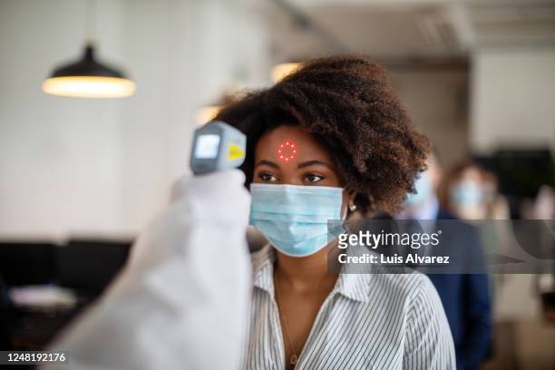woman going through a temperature check before going to work in office - symptom stock pictures, royalty-free photos & images