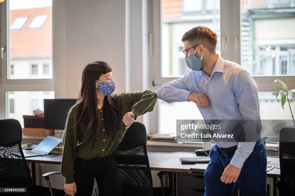 Business people greeting with elbow bump in office