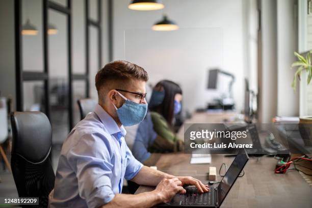 business people maintaining social distance while working in office - face mask coronavirus stock-fotos und bilder
