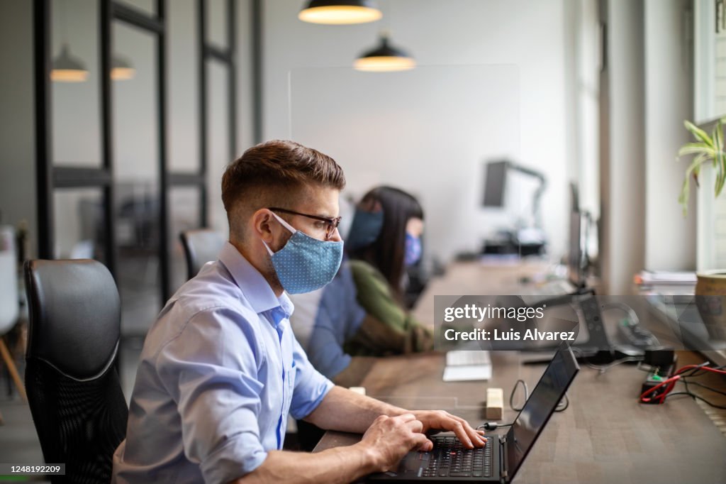 Business people maintaining social distance while working in office