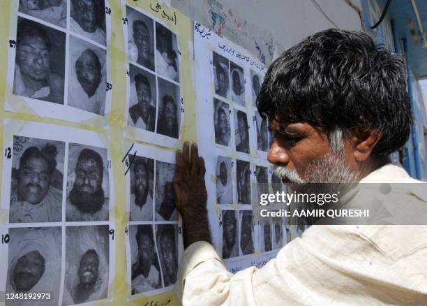 Pakistnai worker of a morgue, run by a private charity Edhi Foundation, pastes photographs of the people who were killed on 18 October in the suicide...