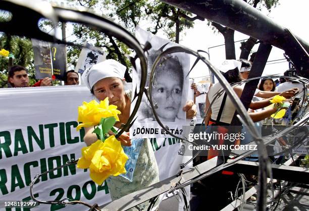 Salvadorean mother places a portrait of her son on a barberwire near the Presidential House 04 November 2004, as part of a rally of relatives who...