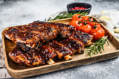Delicious barbecued ribs seasoned with a spicy basting sauce and served with baked tomatoes. Gray background. Top view