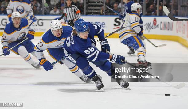 William Nylander of the Toronto Maple Leafs grabs a puck against JJ Peterka of the Buffalo Sabres at Scotiabank Arena on March 13, 2023 in Toronto,...
