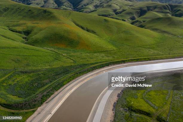 In an aerial view, the California Aqueduct winds through new green grasses during a break between storms on March 13, 2023 near Wheeler Ridge,...