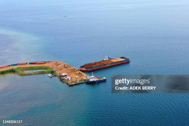 This aerial picture taken on February 7, 2023 shows a general view of a jetty and a barge with soil containing nickel ore as part of an operation by...