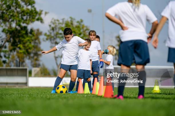 joven futbolista masculino haciendo ejercicio de regate alrededor de conos - ejercicio de entrenamiento deportivo fotografías e imágenes de stock