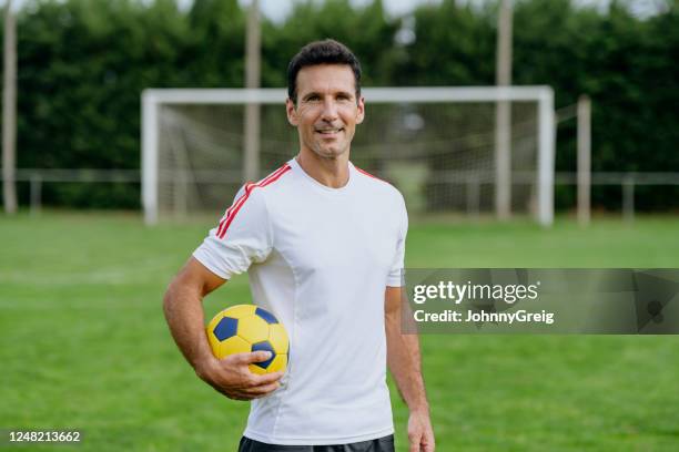 porträt eines reifen männlichen fußballers auf dem feld mit ball - soccer men stock-fotos und bilder