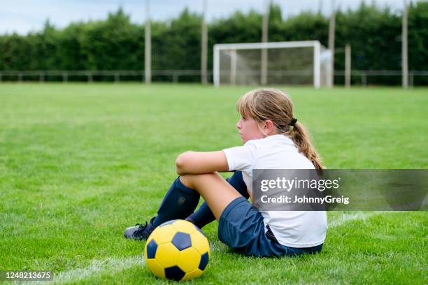 serious 9 year old female footballer sitting on sideline - football sideline stock pictures, royalty-free photos & images