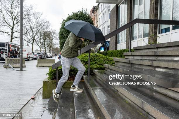 One of the accused hides his face underneath an umbrella as he arrives for a session of the case before the Antwerp appeal court, a remark of the...