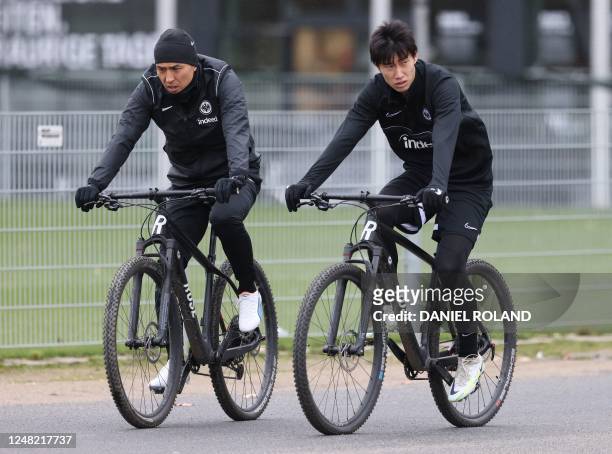 Frankfurt's Japanese midfielder Daichi Kamada and Frankfurt's Japanese midfielder Makoto Hasebe arrive on bicycles for a training session on the eve...