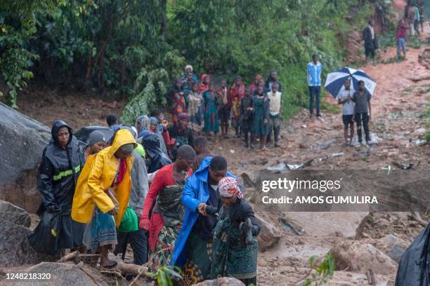 People walk up a hill in Blantyre on March 14 following cyclone Freddy's landfall. - Cyclone Freddy, packing powerful winds and torrential rain,...